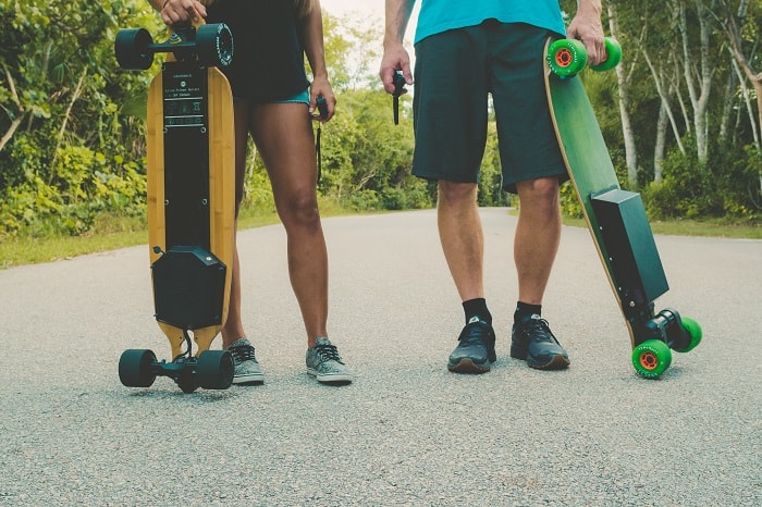 a man and a woman holding electric skateboards