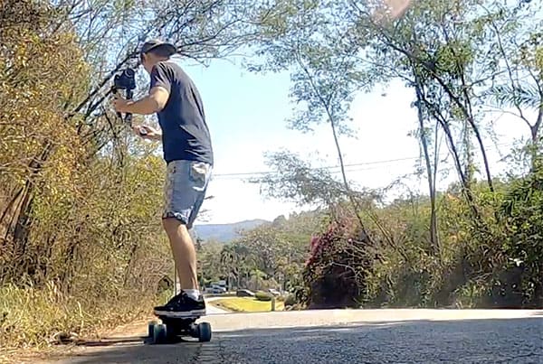 carrying a camera riding an electric skateboard, filming a review